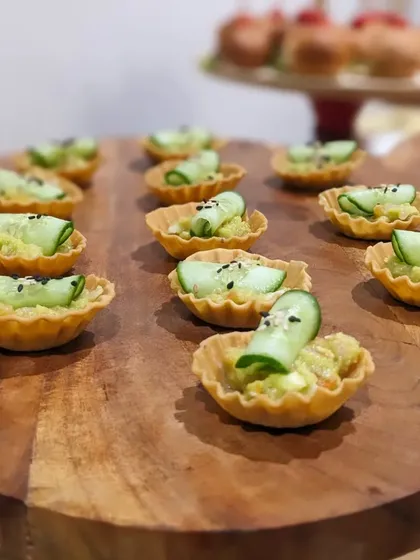 Avocado mousse tarts topped with a slice of cucumber and black sesame seeds. A refreshing, creamy, and healthy canapé option for guests.