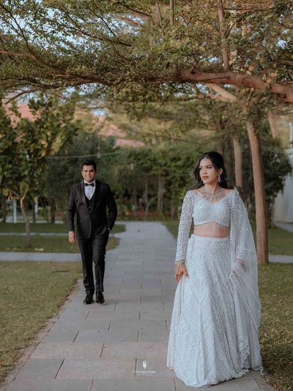 The couple walking on a path in a garden during their reception, a classic and elegant shot.