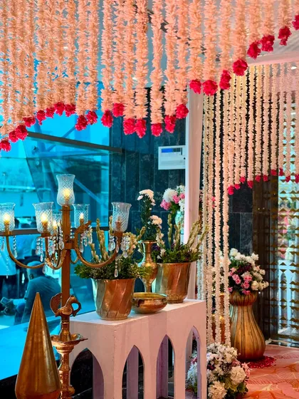 An elegant decor corner featuring a candelabra, brass pots, and hanging floral strings, creating a sophisticated and warm welcome for guests.