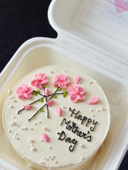 A beautiful floral design for Mother's Day. This bento cake is decorated with piped pink cherry blossoms, capturing a delicate and artistic feel.