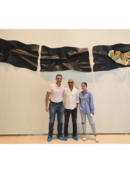 With the happy clients in front of their newly installed 13-foot custom wall sculpture.