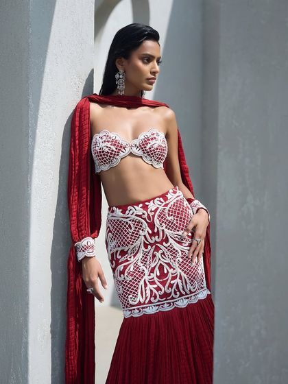 Crimson dreams, pearl-drenched seams. This fish-cut lehenga features intricate pearl embroidery and is paired with a crushed fabric dupatta that speaks in whispers.