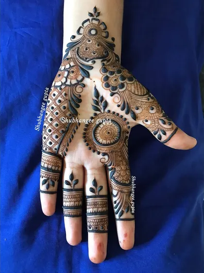 This unique design combines a central mandala on the palm with a flowing paisley pattern on the fingers and wrist. It's a modern, artistic take on traditional mehndi.