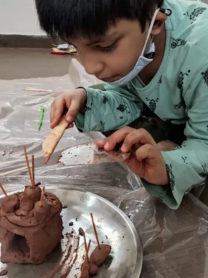 Every detail matters when you're a focused young sculptor. This child is carefully adding the final touches to his clay creation, demonstrating the fine motor skills and attention to detail that these activities nurture.