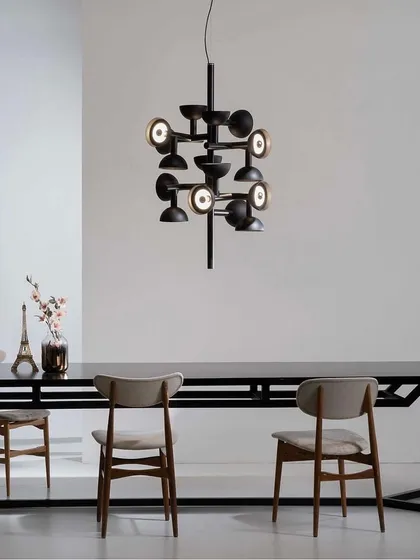 The Sibilla chandelier over a long dining table. Its creative geometric combination changes depending on the viewpoint, making it a dynamic and engaging fixture.