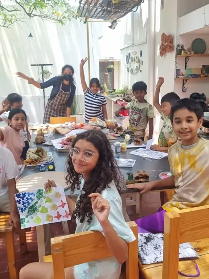 Our kids' camps are all about joyful exploration. This happy group is showing off their block printing creations, just one of the many activities we do, including clay sculpting, paper mache, and tie-dye.