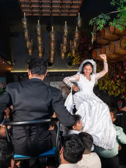 A classic wedding tradition with a fun twist! The bride is lifted on a chair during the reception party, celebrating with all her guests around her. It’s pure, chaotic joy.