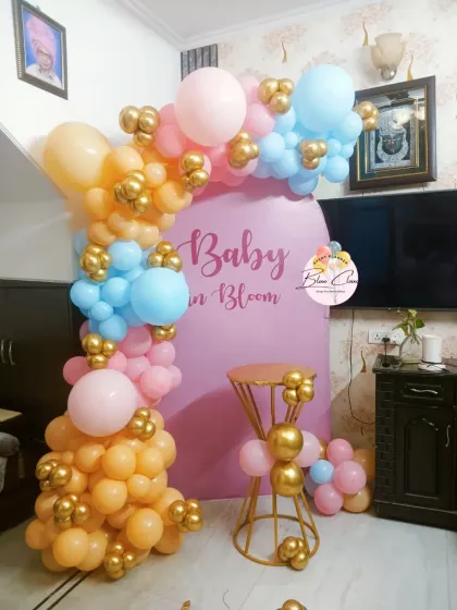 A 'Baby in Bloom' themed baby shower with a pastel pink and blue balloon garland against a custom backdrop.