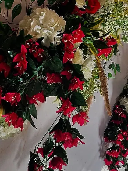 A detailed view of a floral arrangement, showcasing a vibrant mix of red bougainvillea and white carnations. The careful combination of colors and flower types is key to our design process.