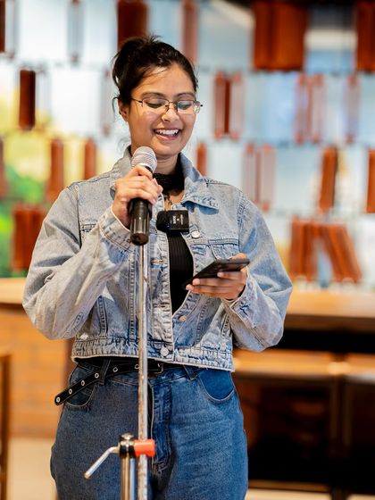 A poet shares her work on the "Wheel of Life" theme. The supportive atmosphere encourages personal and reflective performances.