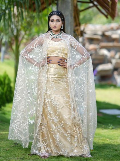 A full-length view of the golden cape lehenga, showing its elegant silhouette and flow. Perfect for a sangeet or reception.