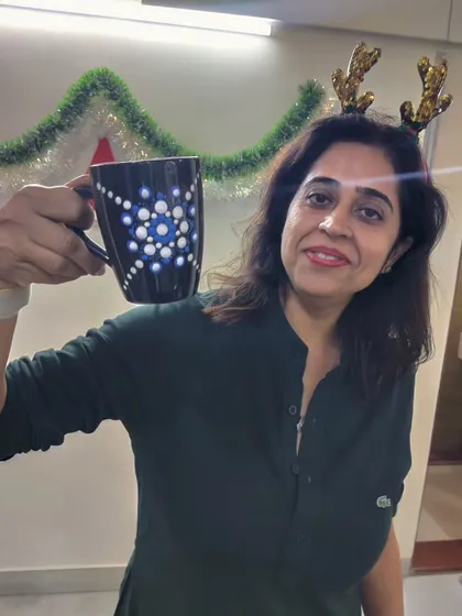 A guest in festive attire holds up her dot mandala mug during a fun-filled Christmas art party.