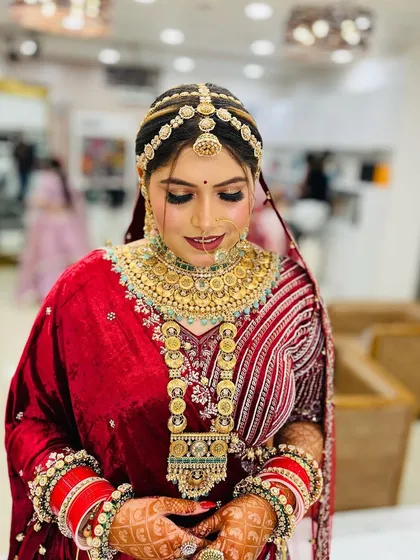 A stunning bride adorned with heavy, traditional jewelry. Her makeup is kept classic and elegant to balance the opulence of her accessories and velvet lehenga.