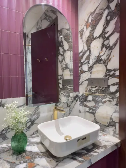 Who says you can't be bold with color in a bathroom? The combination of rich pink subway tiles and dramatic black and white marble creates a powder room that is playful, chic, and full of personality.