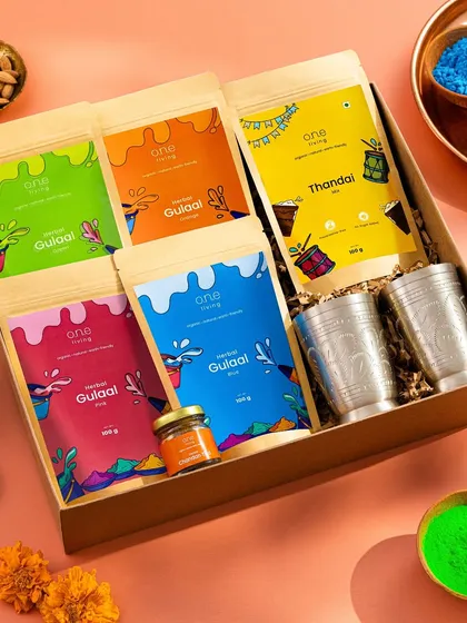 A vibrant flatlay of a Holi-themed gift box. We arranged the colorful herbal gulal packs, Thandai mix, and traditional glasses in a beautiful composition, surrounded by loose colors to capture the joyful spirit of the festival.