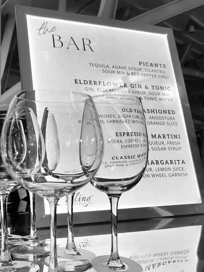 A black and white shot emphasizing the elegant glassware and custom menu design. The clean typography and simple framing make the drink offerings clear and stylish.