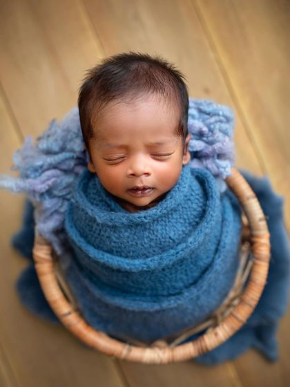 A top-down view of the baby boy wrapped in blue. This angle is great for showing off their sweet, sleepy faces.