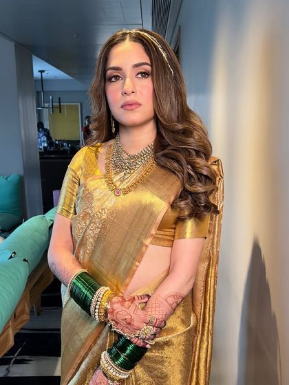 This shot captures the rich texture of the golden silk saree and how the makeup's warm tones complement it perfectly. The bride looks absolutely regal.