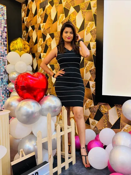 A guest posing with the balloon decorations. The picket fence and heart-shaped balloon are part of a popular theme for birthdays and romantic events.