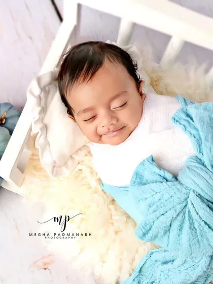 A sweet, sleepy smile from the baby in the blue pumpkin setup.