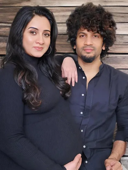 A modern and chic couple's portrait. Both partners are dressed in stylish black outfits, posing together against a wooden wall for a contemporary and sophisticated look.