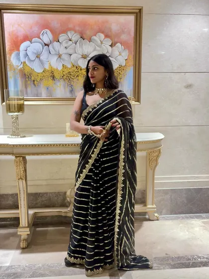 A full-length shot of the black saree against a neutral background. This classic Indian wear is versatile and perfect for any formal celebration.