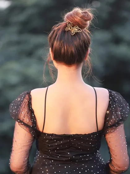 A detail shot from the same series, highlighting the butterfly hair clip and the back of the dress.