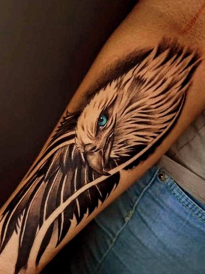 A design concept for a stylized eagle tattoo. The sharp, graphic lines and the piercing blue eye create a modern and edgy look, perfect for a forearm piece.
