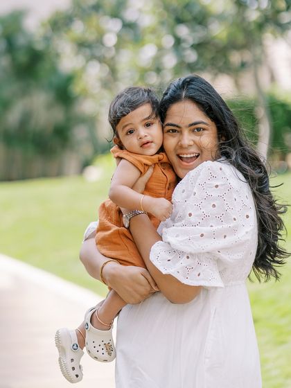 A mother holding her baby, both looking happy and relaxed. The joy of motherhood shines through in this beautiful outdoor portrait.
