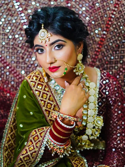 A confident portrait of the bride, showcasing the rich colors and textures of her outfit, perfectly complemented by the student's makeup.