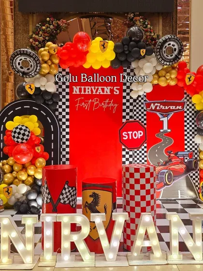 A detailed look at the Ferrari race car themed birthday stage, with tire props, checkered patterns, and the birthday boy's name in lights.