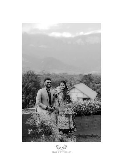 A classic black and white portrait of a Muslim couple in their reception attire, set against a beautiful mountain backdrop.