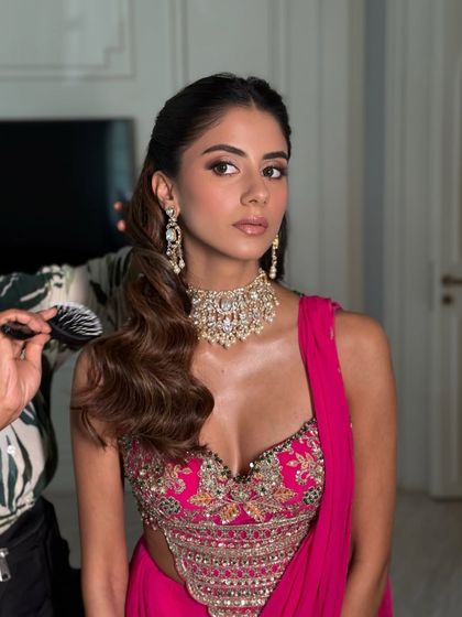 A behind-the-scenes shot showing the hairstylist at work, giving a glimpse into the full glam process.