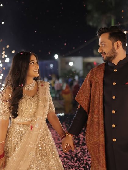 A romantic walk under the fireworks. The bride's makeup glows beautifully in the dramatic lighting.