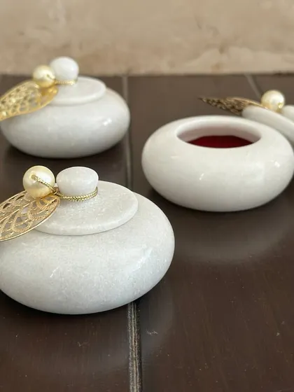 These white marble-finish kumkum holders are a sophisticated and elegant shagun gift. The gold leaf and pearl detail on the lid adds a touch of luxury.