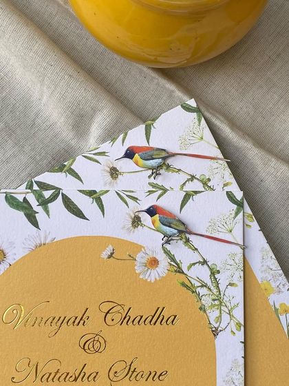 A close-up of the invitation, showing the hand-applied sunbird illustration. I combined florals common to both India and the UK, like daisies and buttercups, to represent the couple's union.