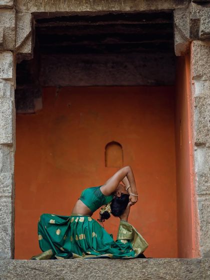 A deep backbend in Eka Pada Rajakapotasana (King Pigeon Pose), framed by ancient stone architecture.