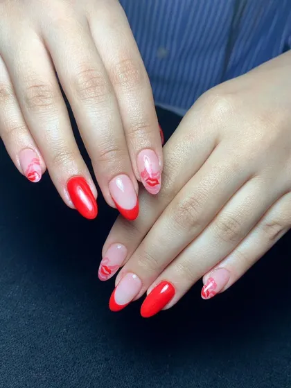 A fun and flirty design with bright red nails, red French tips, and accent nails with a playful lip print.