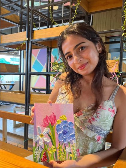 A participant holds up her beautiful floral texture painting. Using palette knives and thick acrylics, you can create stunning 3D effects on canvas.