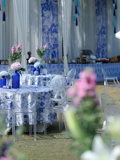 Another view of the dining area, with the camera focused through foreground flowers, creating a soft and dreamy image of the blue and white tables.