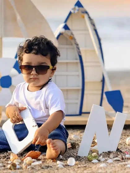 A cool little dude celebrating his first birthday on the beach with a nautical theme, complete with sunglasses.