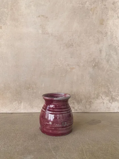 A small, grooved pot with a rich, glossy red glaze. Even simple pieces can be transformed by the magic of firing.