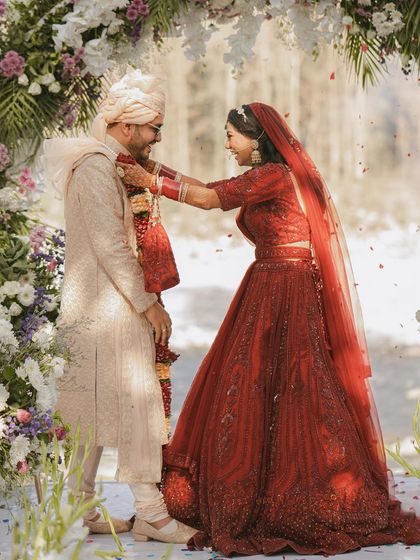The bride playfully places the garland on the groom during their Jaimala ceremony, a moment of fun and love.