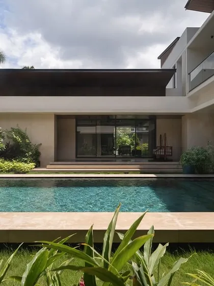 The pool court at Villa Shakthi is designed as the heart of the home. This view from the garden shows how the living spaces open directly onto the pool deck, blurring the lines between inside and out in a way that is ideal for tropical settings.