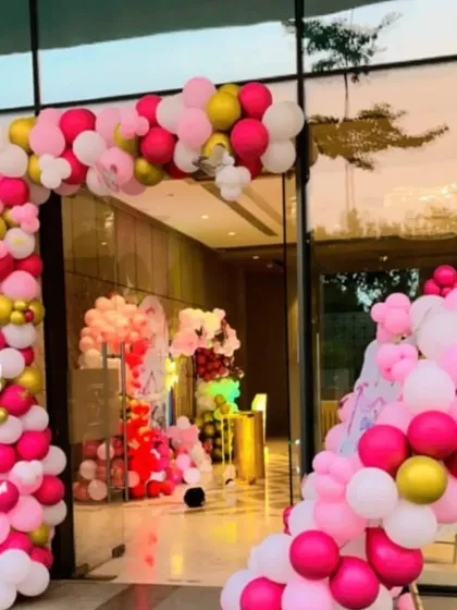 A grand entrance for a pink-themed party. A large balloon arch in shades of pink and gold welcomes guests into the venue.