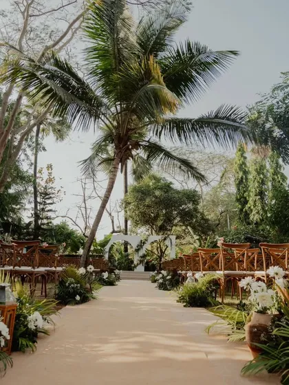An outdoor engagement ceremony path I designed, lined with lush greenery and white floral arrangements. The aisle leads to a simple, elegant arch, creating a beautiful, natural setting for the couple to exchange rings.
