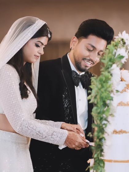 The couple cuts their beautiful multi-tiered wedding cake together. This classic engagement party moment is captured with a focus on their happy interaction.