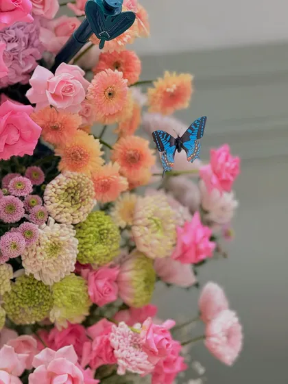 A close-up of a vibrant floral arrangement, with artificial butterflies adding a touch of whimsical magic.