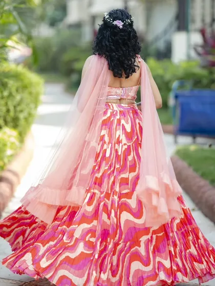 This Haldi hairstyle features natural curls in a half-updo, adorned with a small floral accessory. It's a fun, fresh, and practical style that keeps the hair managed during the ceremony.