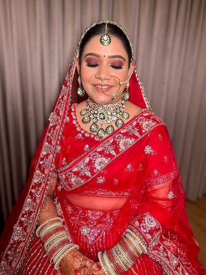 The complete look with the dupatta. The red lehenga, green jewelry, and brown smokey eyes come together to create a breathtaking bridal look.